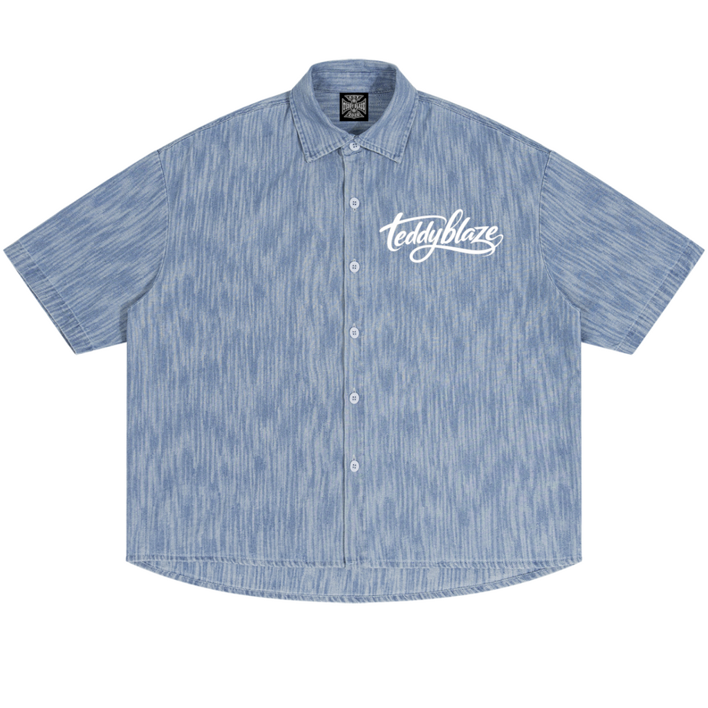 Shop the Signature Boxy Vintage Wash Denim Camp Shirt by Teddy Blaze. 230 GSM lightweight washed blue denim camp shirt with white script branding from HIGH ROLLERS OUTERWEAR.