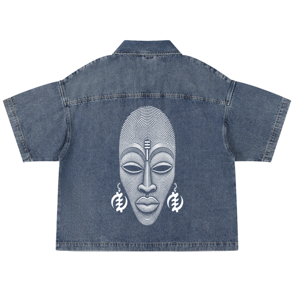 A blue denim short-sleeve shirt shown from the back, featuring a large white graphic print of an African-style face with geometric line details and matching earrings.
