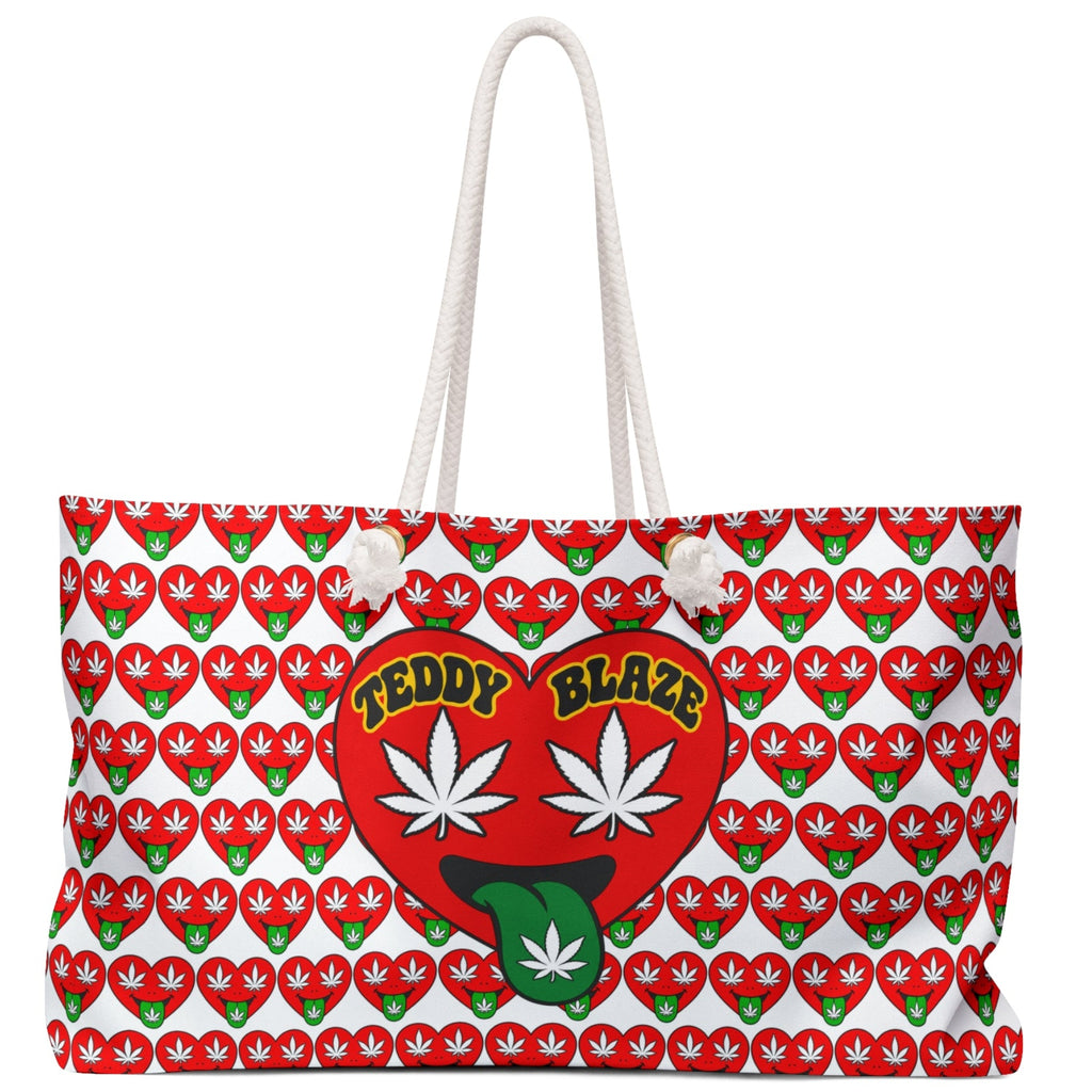A white canvas tote bag with a red and green repeating cannabis leaf pattern, featuring a large red heart graphic on the front with the words 'TEDDY BLAZE' and two white cannabis leaves.