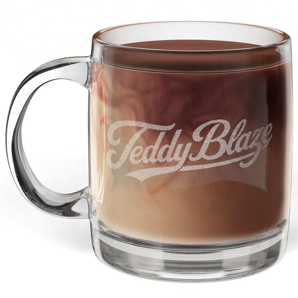 A clear glass mug filled with a brown coffee drink, featuring the words 'Teddy Blaze' printed in white script on the front, set against a plain white background.