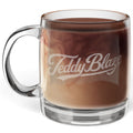 A clear glass mug filled with a brown coffee drink, featuring the words 'Teddy Blaze' printed in white script on the front, set against a plain white background.