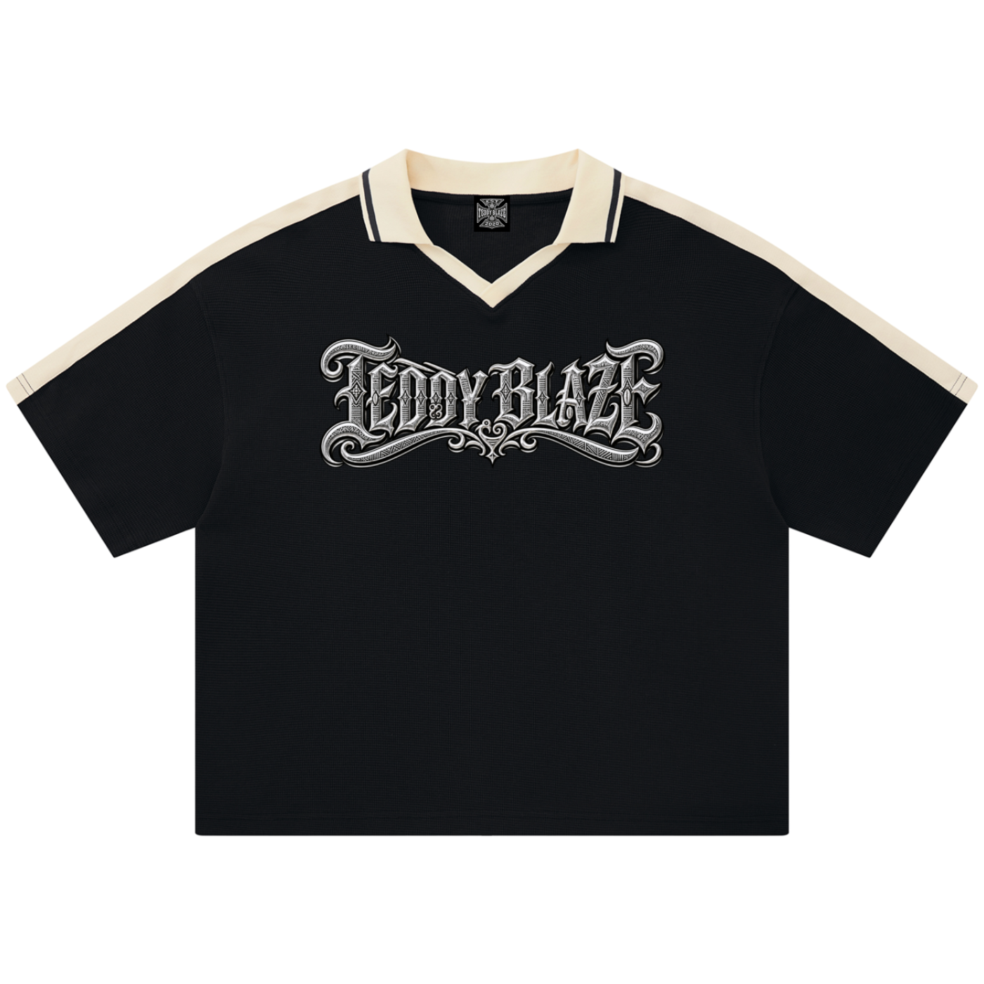 A black short-sleeve polo shirt with cream-colored shoulder panels and collar trim, featuring a large silver gothic 'TEDDY BLAZE' graphic across the chest, displayed on a clean white background.