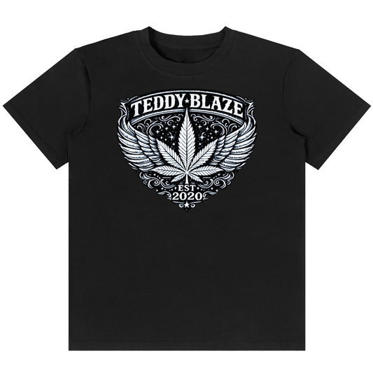 A black short-sleeve crewneck t-shirt featuring a white graphic print on the front. The graphic displays a stylized cannabis leaf with wings, surrounded by the text 'TEDDY-BLAZE' at the top and 'EST.