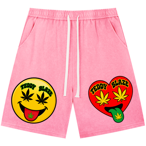Pink drawstring shorts with a yellow smiley face graphic and a red heart graphic on the front, both featuring the text 'TEDDY BLAZE' and cannabis leaf motifs, shown on a plain white background.