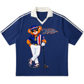 A short-sleeve navy blue polo shirt with a white V-neck collar and white shoulder stripes, featuring a large graphic of a cartoon bear dressed in a blue and orange golf outfit holding a club. The shirt is displayed flat against a solid white background.