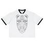 A white ringer t-shirt with black trim on the collar and sleeve cuffs, featuring a large black line art graphic of a tribal-style face on the front.