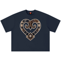 A navy blue short-sleeve t-shirt with a large heart-shaped graphic on the chest. The graphic features a patchwork design of brown plaid, beige stripes, and white beaded borders, with a small black and white clover motif at the bottom center.