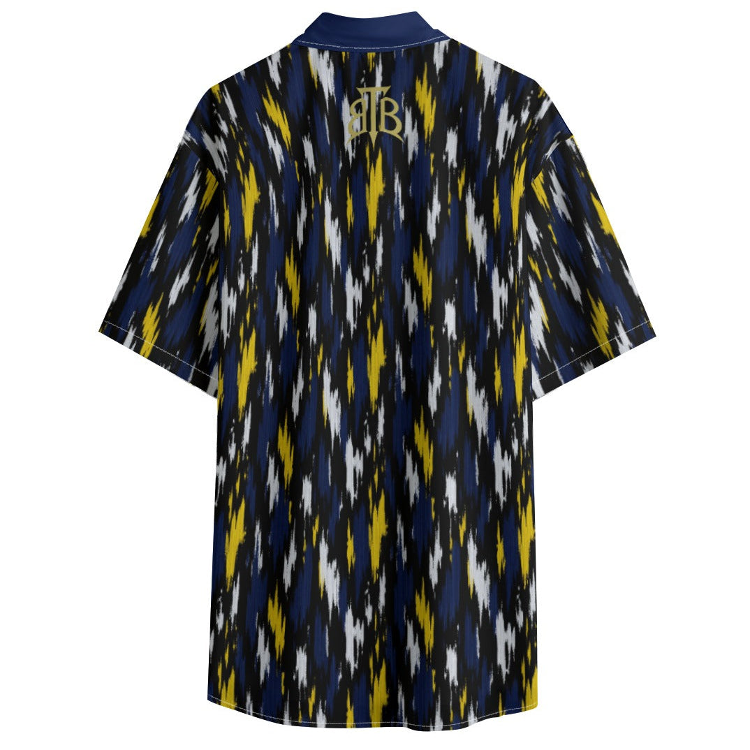 A short-sleeve button-up shirt shown from the back, featuring a navy blue, yellow, and white ikat pattern with a gold monogram logo at the collar.