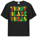 A black short-sleeve t-shirt with a colorful graphic on the chest reading 'TEDDY BLAZE VEGAS' in a distressed, textured font using green, yellow, and red colors, shown against a plain white background.