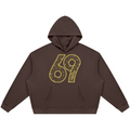 A dark brown cropped hoodie with a large yellow '69' graphic printed on the chest, featuring a detailed mandala pattern inside the numbers.