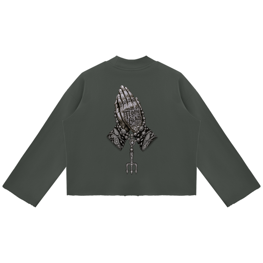 Elevate your cold-weather wardrobe with the Teddy Blaze Sin City Mock Neck Raw Edge Box Cut Jumper. Olive green heavy fleece, mock neck, raw hem, and tattoo praying hands print. Shop NYC to Vegas style.
