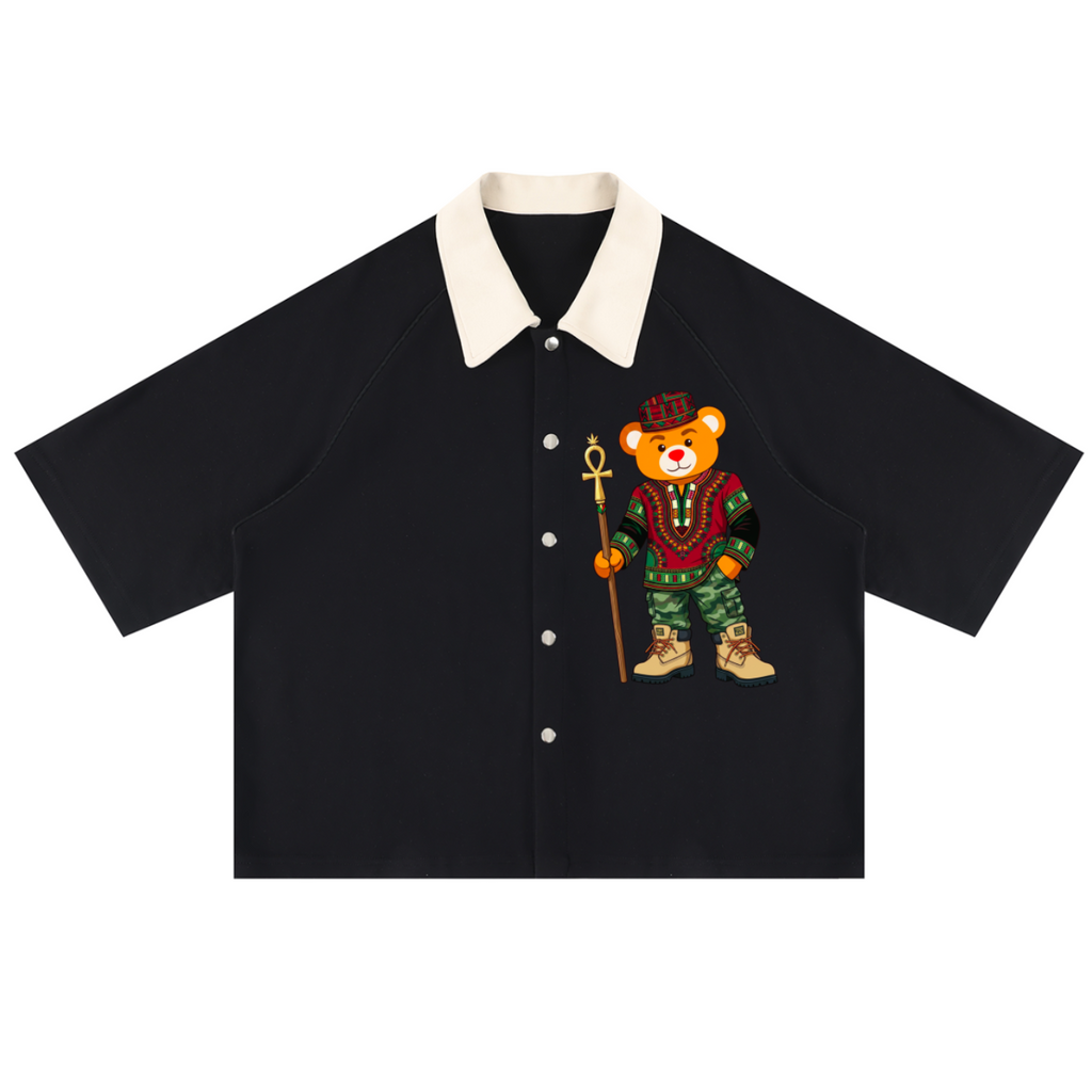 A black short-sleeve button-up shirt with a contrasting cream collar, featuring a graphic of a teddy bear dressed in a green military uniform and holding a spear on the left chest.