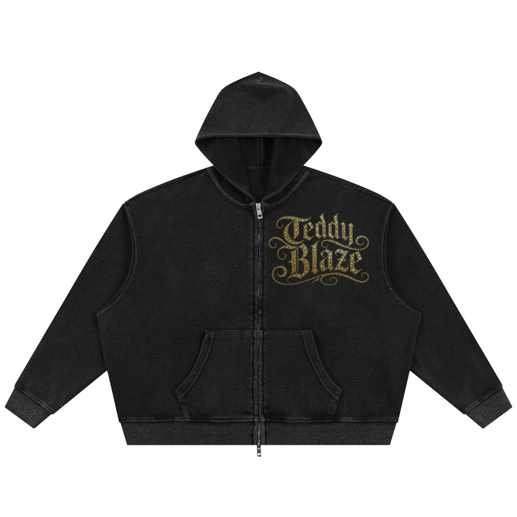 A black zip-up hoodie with a front pocket and a gold 'Teddy Blaze' graphic on the left chest, displayed against a solid white background.