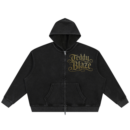 A black zip-up hoodie with a front pocket and a gold 'Teddy Blaze' graphic on the left chest, displayed against a solid white background.