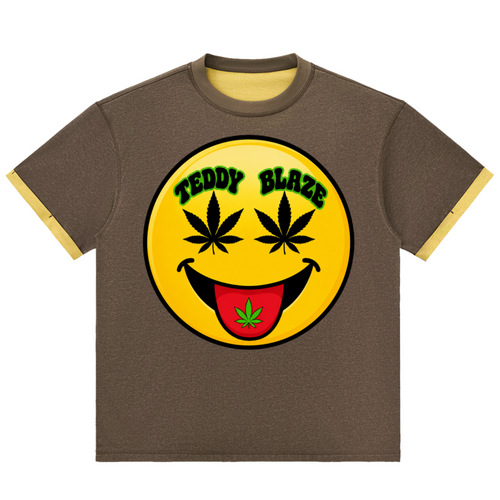 A brown ringer t-shirt with a large yellow smiley face graphic on the chest. The graphic features cannabis leaves for eyes, a black smile, and a red tongue with a green leaf.
