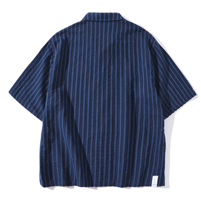Shop the Teddy Blaze Indigo Scholar Stripe Camp Shirt, a relaxed 100% cotton short-sleeve shirt with indigo vertical stripes, camp collar and easy oversized fit.