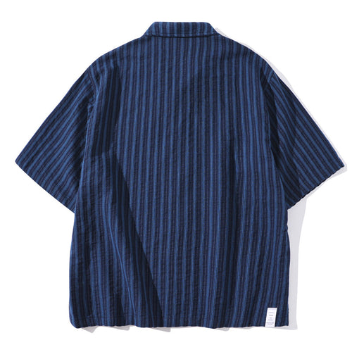 Shop the Teddy Blaze Indigo Scholar Stripe Camp Shirt, a relaxed 100% cotton short-sleeve shirt with indigo vertical stripes, camp collar and easy oversized fit.