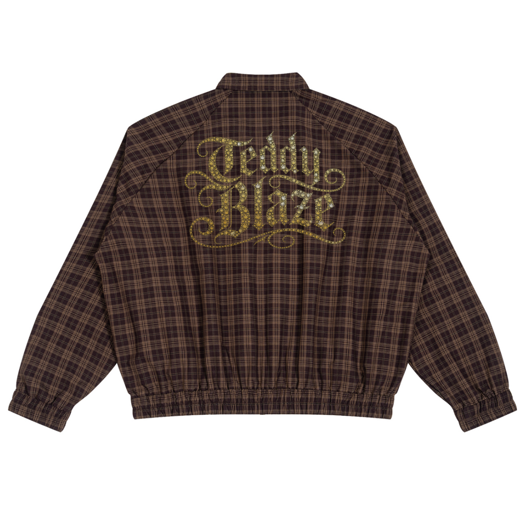 A brown and black plaid jacket shown from the back, featuring a large gold glittery 'Teddy Blaze' logo across the upper back.
