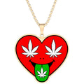 A gold chain necklace with a heart-shaped pendant featuring a red background, white cannabis leaves for eyes, a black smile, and a green tongue also with a white cannabis leaf, shown on a plain white background.