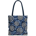 A navy blue tote bag with a white and gray spiral tie-dye pattern, featuring dark navy handles and a small white 'TulaBag' logo patch at the bottom center.