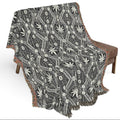 Patterned blanket draped over a chair on a white background