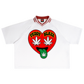 A white short-sleeve T-shirt with a red and white striped collar, featuring a large red heart graphic on the chest with the words 'TEDDY BLAZE' in yellow, white cannabis leaves, and a green tongue sticking out with a cannabis leaf.