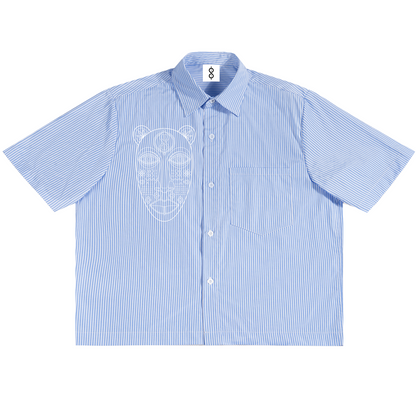 A light blue and white vertically striped short-sleeve button-up shirt with a white line-art graphic of a stylized face on the left chest, displayed flat against a white background.