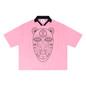 A pink short-sleeve polo shirt with a black collar and a large black line-art graphic of a stylized face on the front, shown against a plain white background.