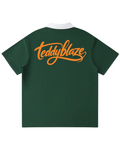 Shop the Iron + Ivy Signature Contrast Collar Raglan Polo by Teddy Blaze. Forest green 220 GSM short-sleeve polo with white contrast lapel collar, raglan sleeves, and orange back script.