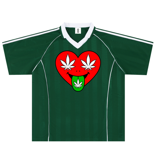 A dark green short-sleeve soccer-style jersey with a white V-neck collar, white shoulder stripes, and a large chest graphic of a red heart with white cannabis leaves and a green tongue.