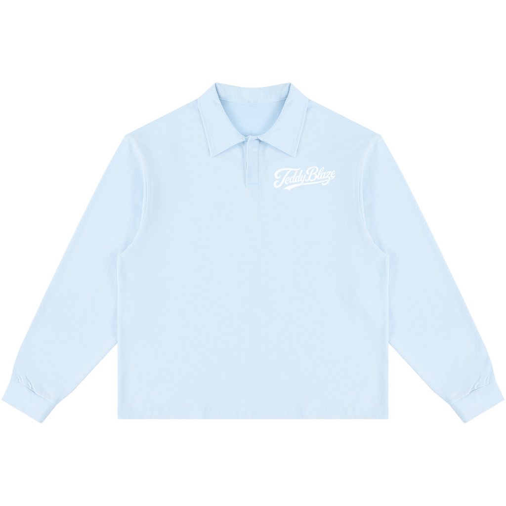 A light blue long-sleeve polo shirt with a white cursive 'Fools Day' graphic on the left chest, displayed flat against a solid white background.
