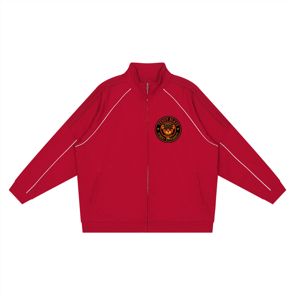 A red zip-up track jacket with white contrast piping along the shoulders and sleeves, featuring a circular black and gold crest patch on the left chest, displayed on a solid white background.