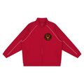 A red zip-up track jacket with white contrast piping along the shoulders and sleeves, featuring a circular black and gold crest patch on the left chest, displayed on a solid white background.