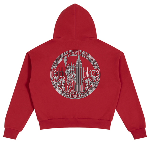 A red cropped hoodie shown from the back, featuring a large circular graphic print in gray with the Statue of Liberty, the Empire State Building, and the text 'teddy blaze'.