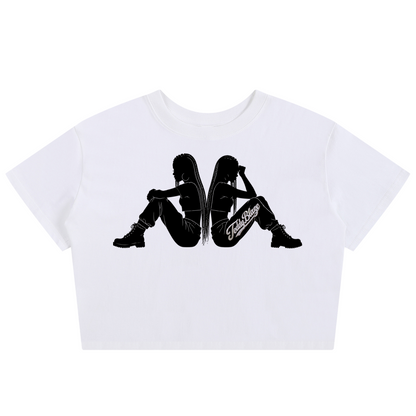A white cropped short-sleeve t-shirt featuring a black graphic print of two silhouetted figures sitting back-to-back, with the word 'Cruel' printed in script across the center.