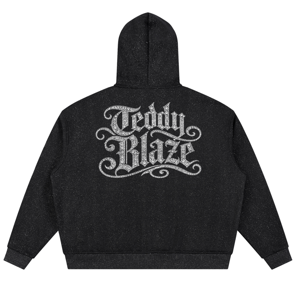 A black heathered hoodie shown from the back, featuring a large, ornate silver glitter-style graphic that reads 'Teddy Blaze' across the upper back.