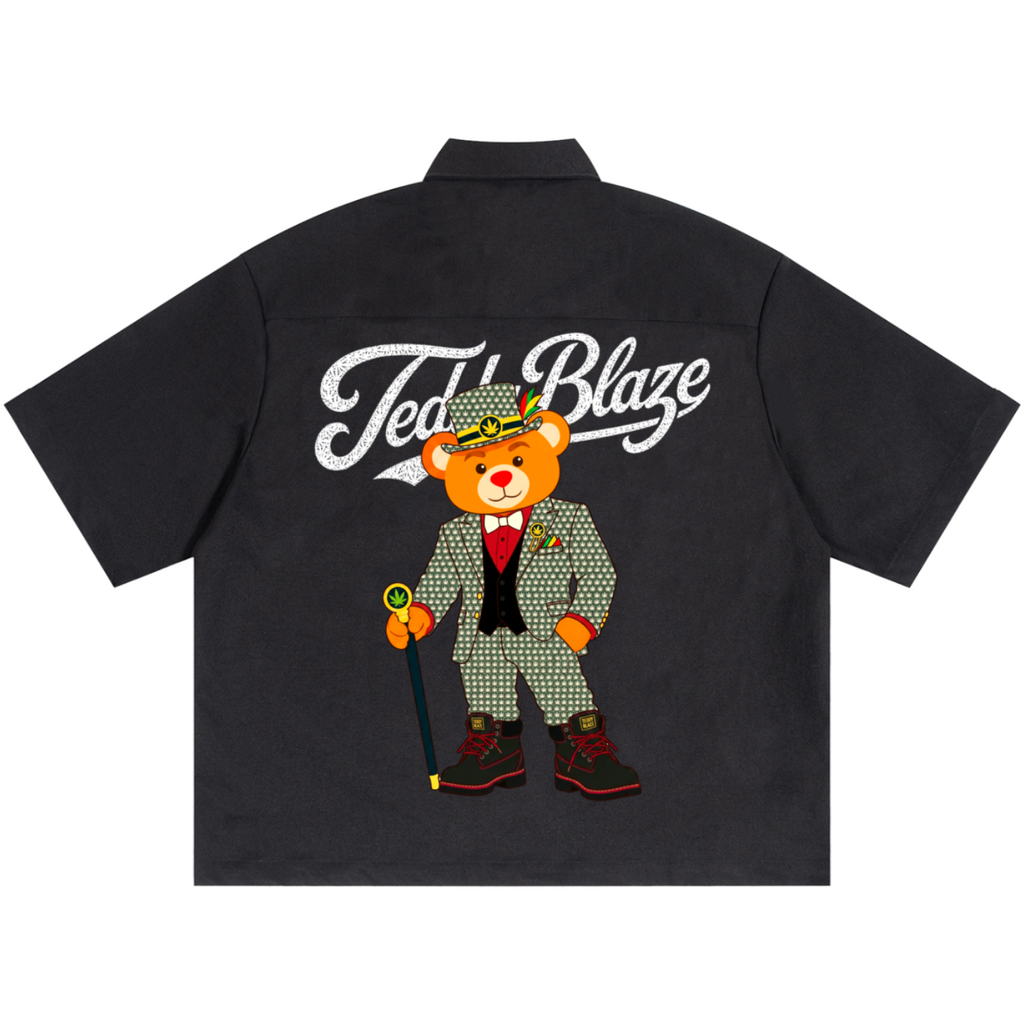 A black short-sleeve button-up shirt shown flat against a white background, featuring a large graphic on the back with the words 'Ted's Blaze' in white script above a cartoon teddy bear wearing a gray patterned suit and holding a cane.