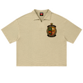 A beige short-sleeve polo shirt with a textured knit fabric, featuring a detailed embroidered crest on the left chest and a red neck label.