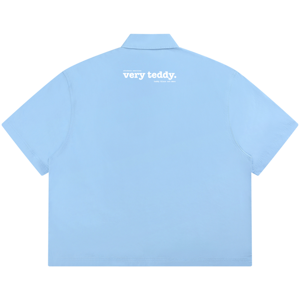Powder-blue 100% cotton boxy Cubano shirt with twin Afrodemia graphics, relaxed unisex proportions and signature VERY TEDDY back branding.