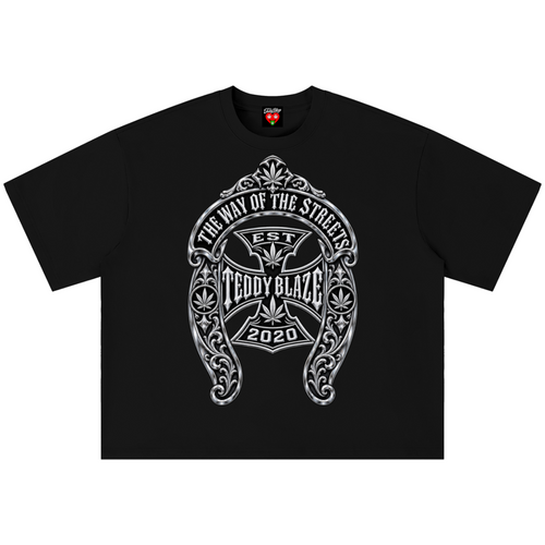 A black short-sleeve crewneck t-shirt featuring a large white and gray graphic print on the front. The graphic is an ornate crest with an iron cross and the text 'THE WAY OF THE SINNER', 'EST TEDDY BLAZE', and '2020'.