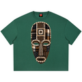 A dark green short-sleeve t-shirt featuring a large, detailed graphic of an African tribal mask on the front. The mask is composed of various patterned fabrics, primarily plaid in brown, beige, and black, with white bead-like accents.