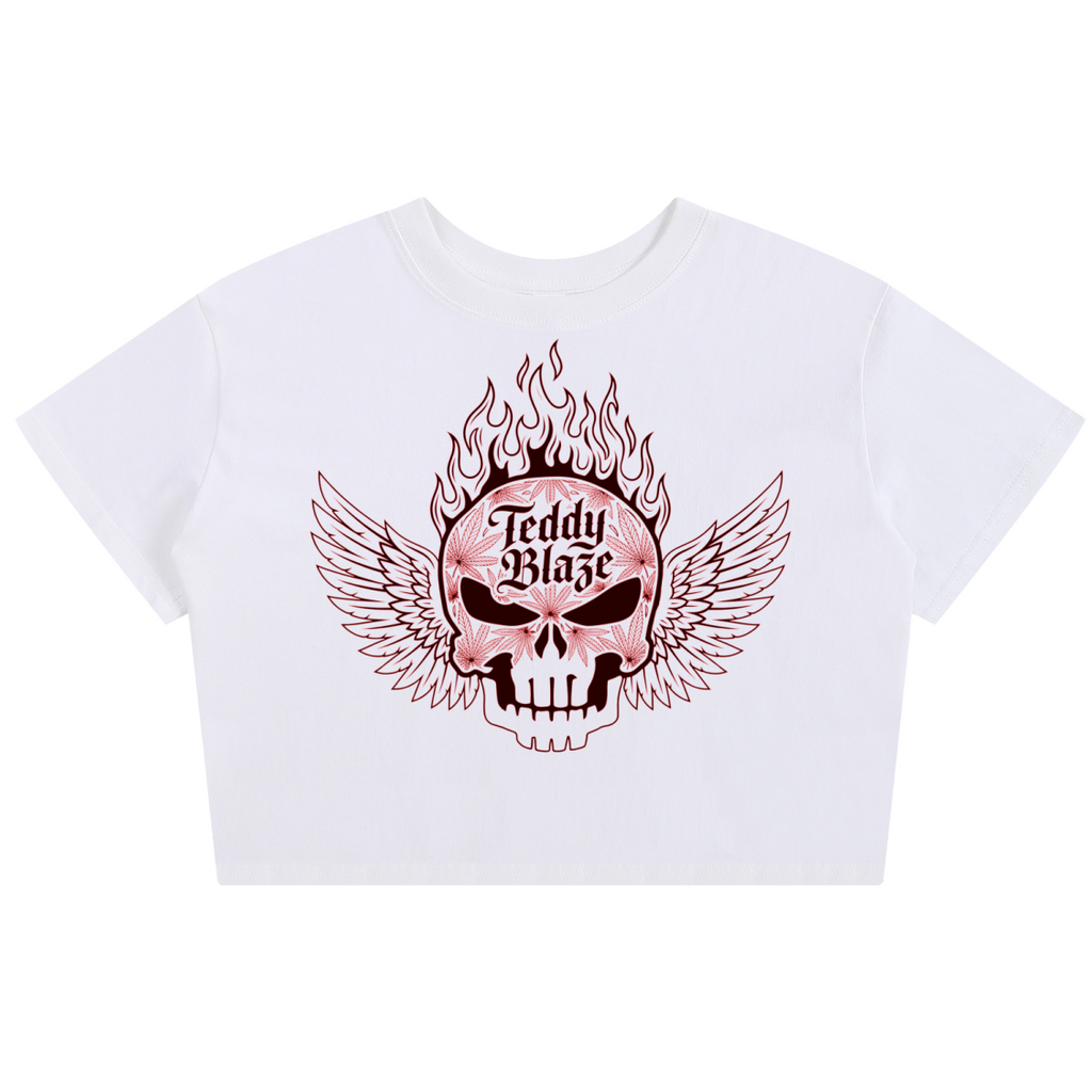 A white cropped short-sleeve t-shirt featuring a graphic print of a winged skull with flames and the text 'Teddy Blaze' on the front, displayed against a solid white background.