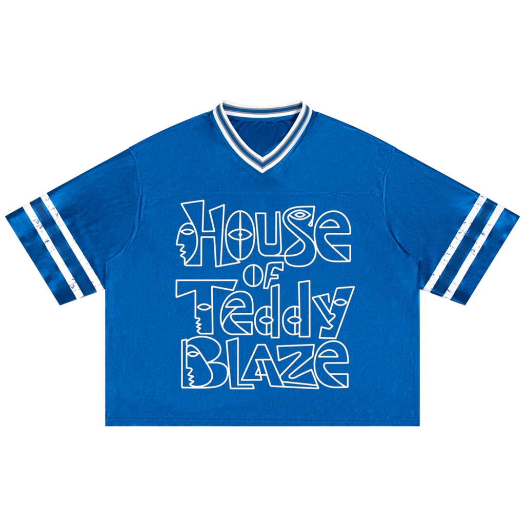 A royal blue short-sleeve V-neck t-shirt with white athletic-style stripes on the sleeves and a large white graphic text reading 'House of Teddy Blaze' across the front.
