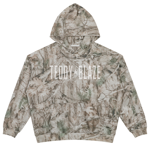 Elevate your streetwear layering with the House of Teddy Blaze No More Wars Tree Camo Fleece Pullover Hoodie. Tree camo 340 gsm fleece, crossover hood, kangaroo pocket, and gothic "No More Wars" back graphic. Shop NYC to Vegas style.