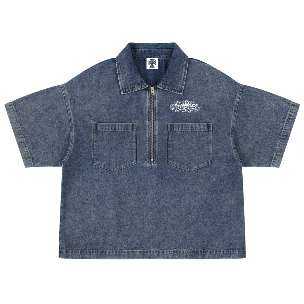 A short-sleeve denim work shirt with a half-zip collar, two front chest pockets, and a white embroidered logo on the left chest, shown flat against a white background.