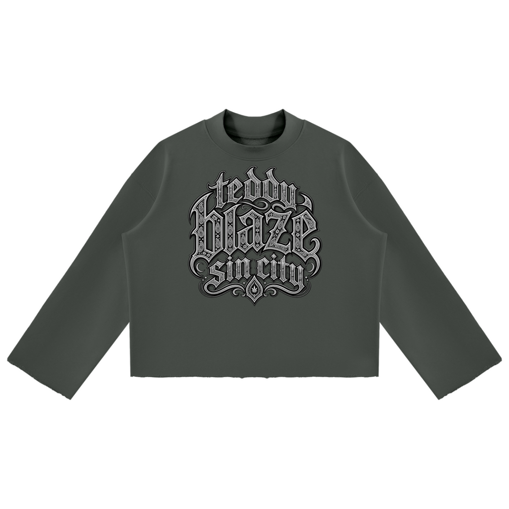 Elevate your cold-weather wardrobe with the Teddy Blaze Sin City Mock Neck Raw Edge Box Cut Jumper. Olive green heavy fleece, mock neck, raw hem, and tattoo praying hands print. Shop NYC to Vegas style.