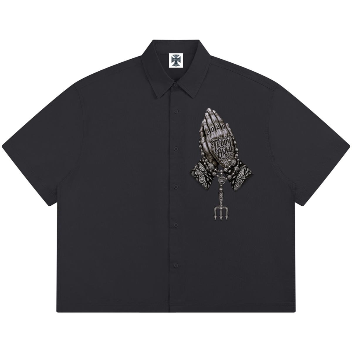 Elevate your resort wardrobe with the Teddy Blaze Sin City Sacred Box Cut Cotton Camp Shirt. Charcoal cotton button-down, lapel collar, and tattoo praying hands print. Shop NYC to Vegas style.