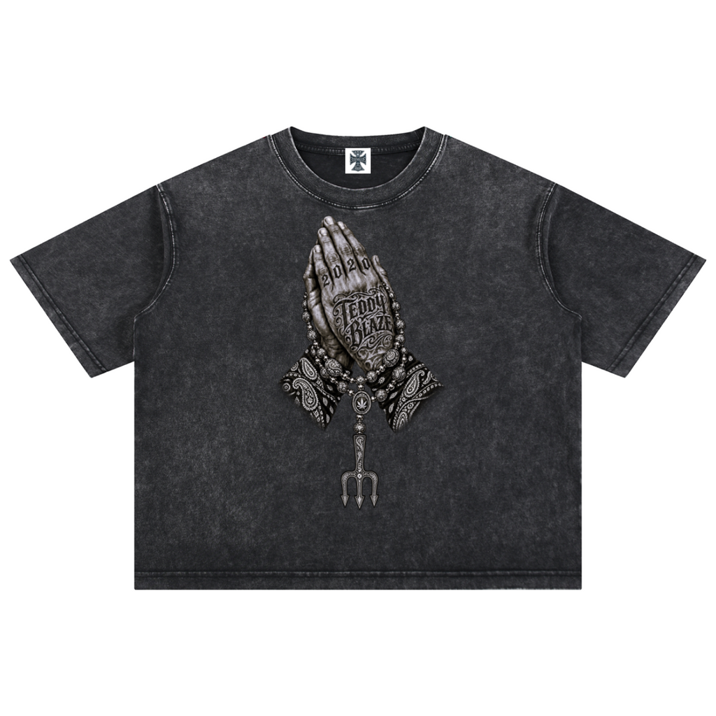 Elevate your streetwear with the Teddy Blaze Sin City Sacred Snow Wash Boxy Cotton Tee. Snow-washed charcoal cotton, tattoo praying hands print, and boxy cut. Shop NYC to Vegas style.