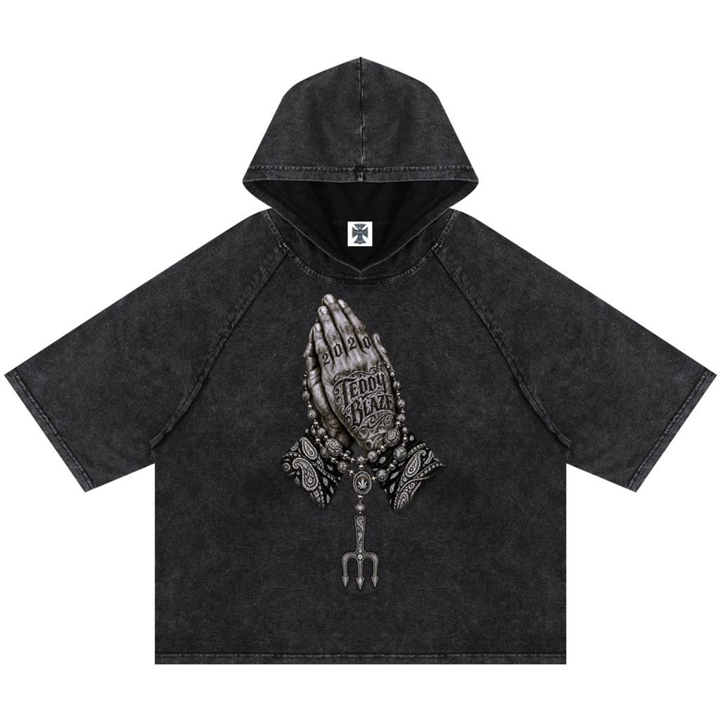 Elevate your casualwear with the Teddy Blaze Sin City Snow Washed Hooded Box Cut Tee. Charcoal snow-washed cotton blend, short raglan sleeves, hood, and tattoo praying hands graphic. Shop NYC to Vegas style.