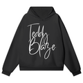 A black pullover hoodie with 'Teddy Blaze' written in a white cursive script across the chest, displayed on a clean white background.